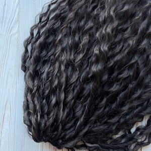 May include: A bundle of dark brown curly hair extensions.