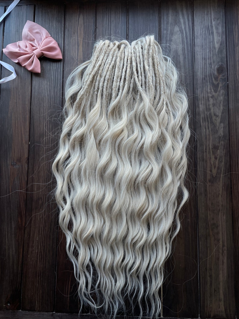 May include: A set of long, wavy, white synthetic dreadlocks. The dreadlocks are arranged in a straight line and are hanging down.