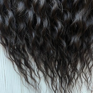 May include: Close-up of dark brown human hair extensions with a wavy texture.