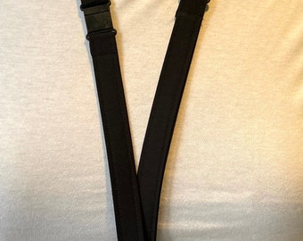 May include: A solid black fabric lanyard featuring adjustable black plastic sliders on each side and a silver-toned metal swivel lobster clasp at the bottom. The lanyard is constructed from a flat, durable textile material with stitched edges.