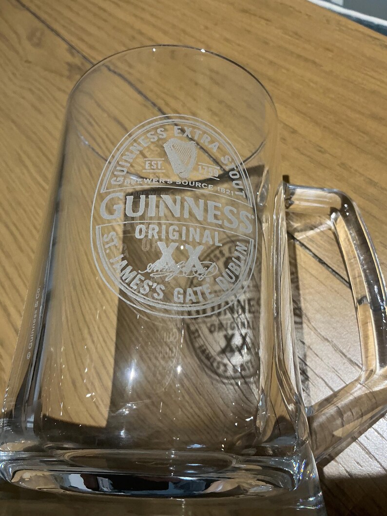 May include: A white ceramic mug with a black handle and the text "But First, Coffee" in a handwritten style. The mug is on a white surface. The mug is likely for hot beverages.