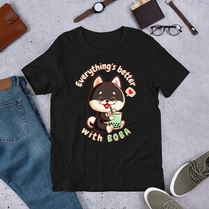 May include: Black t-shirt featuring a cartoon dog holding a boba tea cup. The text on the shirt reads "Everything's better with BOBA".