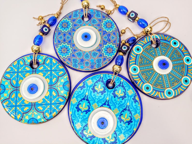 May include: Four blue and gold round ceramic wall hangings with evil eye charms. Each hanging features a different blue and gold geometric pattern.