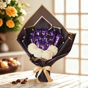 May include: A bouquet featuring multiple purple Cadbury Dairy Milk chocolate bars arranged with four white artificial roses. The arrangement is wrapped in black paper with gold trim and tied with a gold ribbon, creating a structured, fan-like shape.