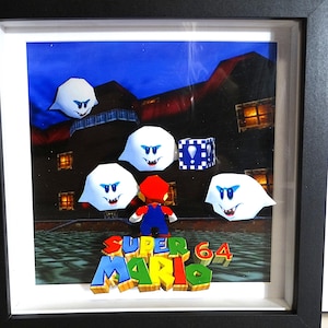 Puede incluir: Obra de arte enmarcada que representa una escena de Super Mario 64. La imagen incluye a Mario, fantasmas blancos con ojos azules y un bloque de interrogación. El título "Super Mario 64" se muestra en letras 3D coloridas.