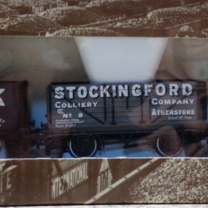 May include: Three miniature model railway wagons, each with a different company name and logo. The wagons are brown, green, and red. The text on the wagons reads "Whitwick G.55", "Stockingford Colliery Co. Ltd.  Attercliffe", and "Newbold & Martell Coal Contractors Southampton".