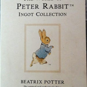 May include: A book cover featuring Peter Rabbit in a blue jacket, running with a white tail. The title is "The World of Peter Rabbit TM Ingot Collection" and the author is Beatrix Potter. The text below the image reads "The original and authorized edition."