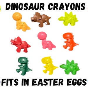 Puede incluir: Nueve crayones de colores con forma de dinosaurio, perfectos para las cacer&iacute;as de huevos de Pascua. Los crayones son de varios colores, incluyendo rojo, verde, amarillo, naranja y marr&oacute;n. El texto "DINOSAUR CRAYONS" y "FITS IN EASTER EGGS" est&aacute; impreso en la imagen.