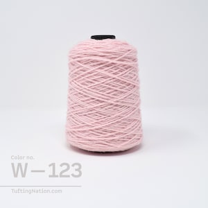 May include: A spool of light pink yarn with the color number W-123. The yarn is wound tightly and has a smooth texture.