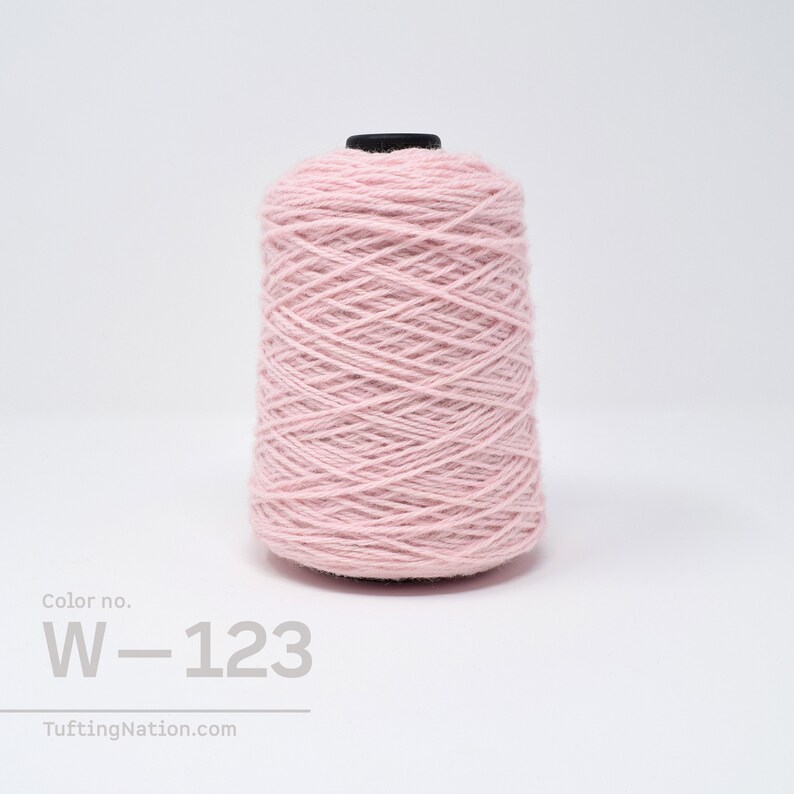 May include: A spool of light pink yarn with the color number W-123. The yarn is wound tightly and has a smooth texture.