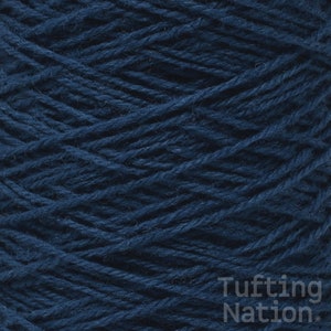 May include: A close-up of a spool of dark blue yarn. The yarn is tightly wound and has a soft, fuzzy texture.
