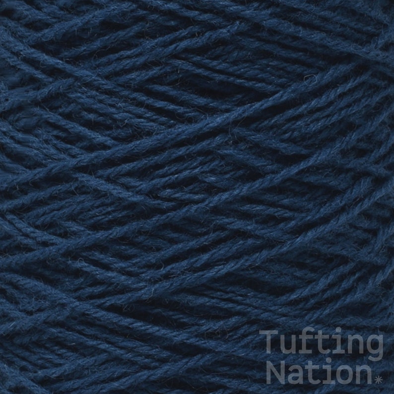 May include: A close-up of a spool of dark blue yarn. The yarn is tightly wound and has a soft, fuzzy texture.