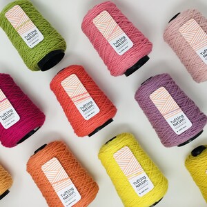 May include: Ten spools of yarn in various colors, including green, pink, red, orange, yellow, and purple. Each spool has a label that reads "Tufting Nation."