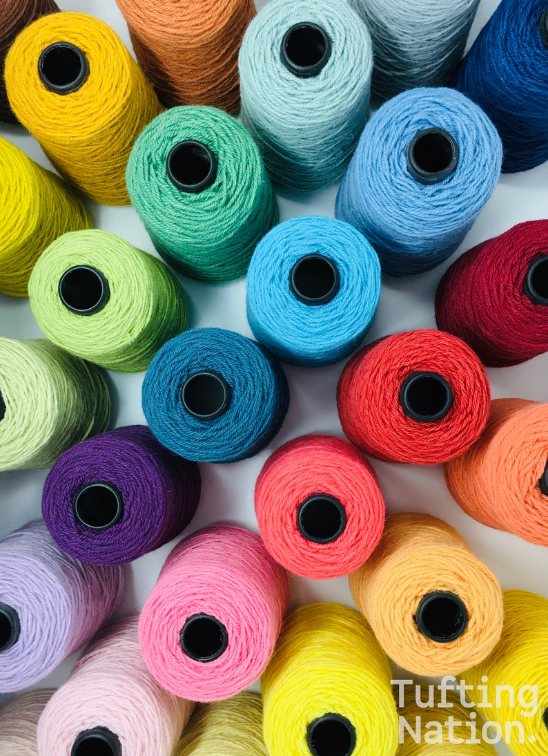 May include: A collection of colorful yarn spools in various shades of blue, green, red, yellow, orange, pink, and purple. The spools are arranged in a circular pattern on a white surface.