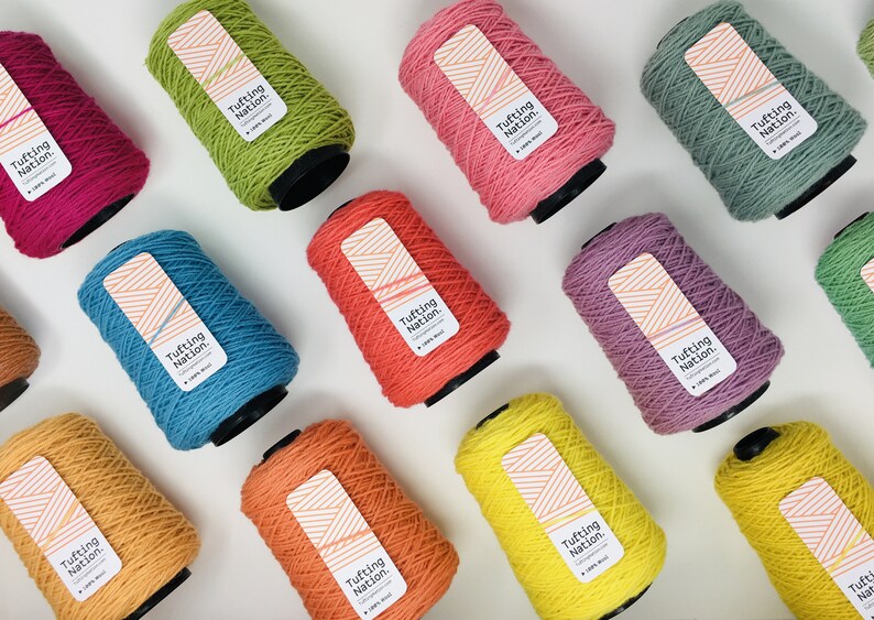 May include: A collection of 10 spools of yarn in various colors, including yellow, orange, red, pink, purple, blue, green, and brown. Each spool has a label that reads "Tufting Nation."