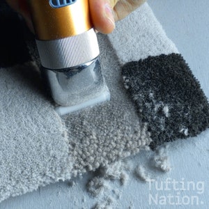 May include: A close-up of a hand holding an electric fabric shaver over a piece of tufted fabric. The shaver is cutting the fabric, creating a pile of fabric fuzz.