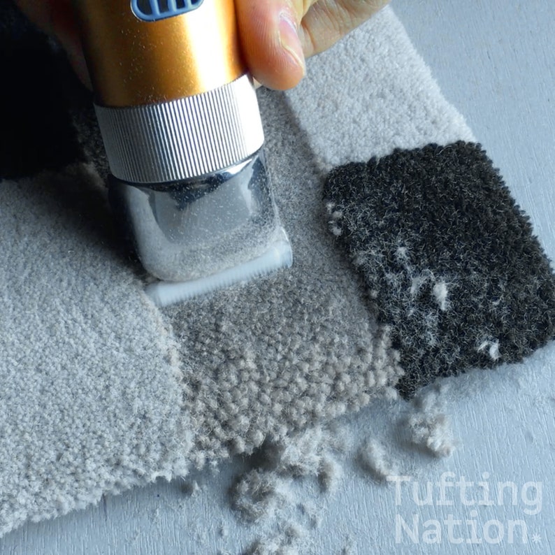 May include: A close-up of a hand holding an electric fabric shaver over a piece of tufted fabric. The shaver is cutting the fabric, creating a pile of fabric fuzz.