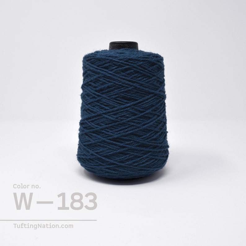 May include: A spool of dark blue yarn, labeled "W-183", for rug hooking or tufting.