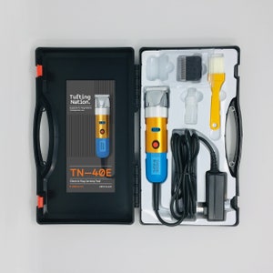 May include: A blue and gold electric rug carving tool with a black cord and a white power adapter. The tool is in a black and white case with the text "Tufting Nation" and "TN-40E Electric Rug Carving Tool" on it.