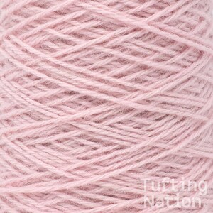 May include: A close-up of a spool of pale pink yarn.