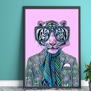 May include: Framed art print featuring a stylized tiger wearing large, square-framed glasses. The tiger is dressed in a patterned blazer, a striped scarf, and a pocket square, set against a pink background. The artwork has a modern, whimsical style.