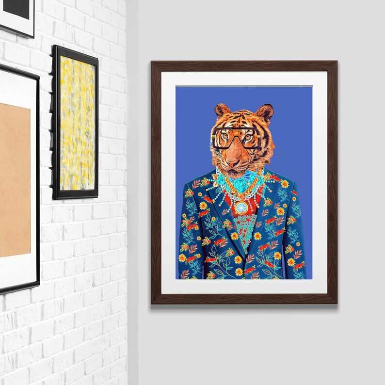 May include: A framed art print depicting a tiger in a blue floral suit, glasses, and jewellery, set against a blue backdrop. The artwork is displayed on a white brick wall, alongside other framed pieces.