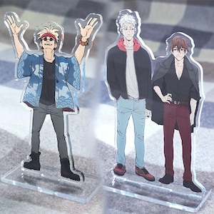 Può includere: Supporti in acrilico con tre personaggi maschili in stile anime. Un personaggio indossa una giacca blu fantasia, occhiali da sole e una fascia rossa. Un altro ha una giacca nera con cappuccio foderato di rosso. Il terzo personaggio indossa una camicia nera e pantaloni rossi.