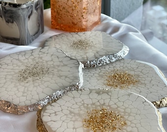May include: Three white resin coasters with gold leaf accents and a silver rim. The coasters have a crackled finish and are perfect for protecting surfaces from heat and spills.