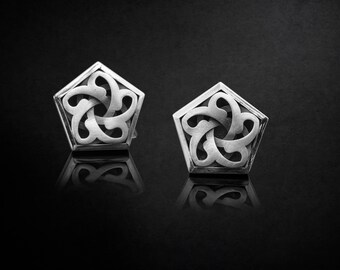 Puede incluir: Un par de gemelos de plata con un diseño geométrico. Los gemelos tienen forma de estrella de cinco puntas con un intrincado patrón de círculos y líneas superpuestos.