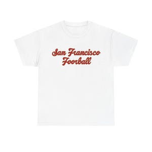 May include: White t-shirt with the words "San Francisco Foorball" in a red, retro-style font. The shirt is a classic crew neck style, perfect for casual wear.