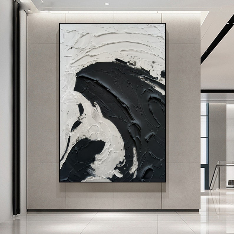 May include: Abstract painting with black and white paint strokes. The painting is framed and hanging on a wall.