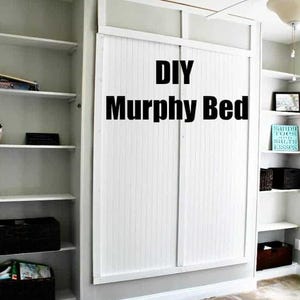 May include: A white DIY Murphy bed with white slatted doors, a white frame, and the text "DIY Murphy Bed" in black lettering. The bed is in a room with white shelves and a ceiling fan.