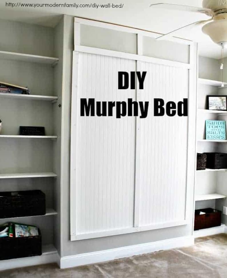 May include: A white DIY Murphy bed with white slatted doors, a white frame, and the text "DIY Murphy Bed" in black lettering. The bed is in a room with white shelves and a ceiling fan.