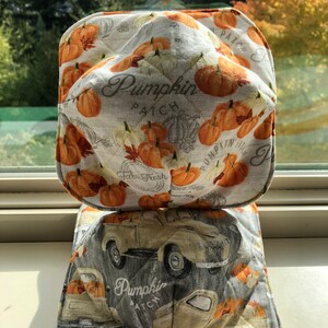 以下が含まれることがあります： パンプキンパッチをテーマにしたキルティング鍋つかみ2枚セット。上の鍋つかみは白地にオレンジ色のカボチャと「パンプキンパッチ」の文字。下の鍋つかみはグレー地にカボチャを積んだビンテージトラックと「パンプキンパッチ」の文字。
