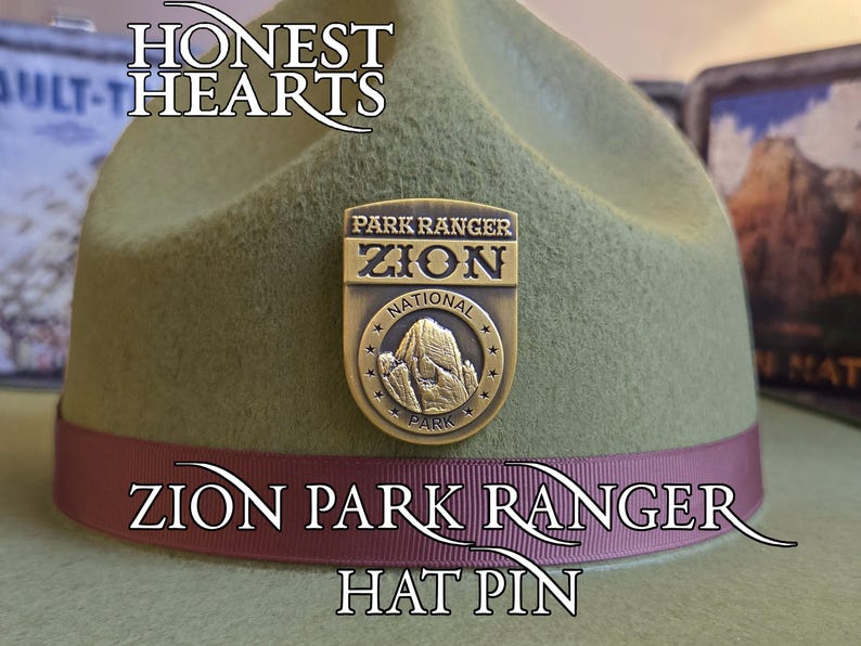 May include: A green hat with a maroon band and a gold-colored pin. The pin reads "Park Ranger Zion National Park" and features a mountain image. Text on the hat reads "Honest Hearts", "Zion Park Ranger", and "Hat Pin".