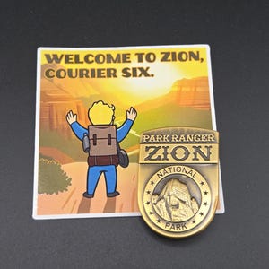 May include: A sticker and a gold-colored metal pin. The sticker reads "WELCOME TO ZION, COURIER SIX." with a cartoon figure. The pin is a Zion National Park Park Ranger badge with a mountain image.