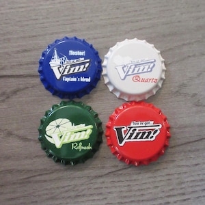 May include: Four circular metal bottle caps featuring the Vim! logo. The top left is blue with 'Tester' and 'Captain's blend'. The top right is white with 'Quartz'. The bottom left is green with 'Refresh'. The bottom right is red with 'You've got... Vim!'.