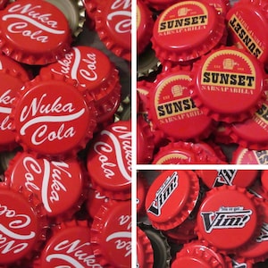May include: A collection of red metal bottle caps featuring white printed logos. The caps display the text Nuka Cola in a cursive script, Sunset Sarsaparilla with a barrel icon, and Vim with the phrase You've got Vim! in a bold, stylized font.