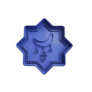 May include: A blue plastic cookie cutter in the shape of an eight-pointed star. Inside the star is a crescent moon, two stars, and a lantern. The cookie cutter is designed for making cookies with a Ramadan theme.