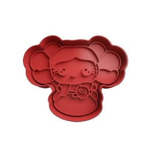 May include: Red plastic cookie cutter shaped like a girl with pigtails holding a flower.