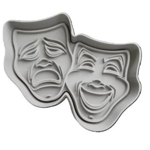 以下が含まれることがあります： 笑顔としかめっ面の2つの劇場のマスクの形をした白いプラスチック製のクッキーカッターです。