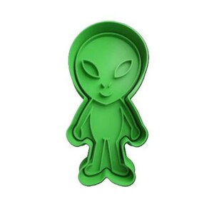 May include: Green plastic cookie cutter shaped like an alien with large eyes and a small mouth.