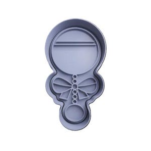May include: A pale blue plastic cookie cutter shaped like a lollipop with a bow. The lollipop features a circular top with a horizontal line, a bow in the middle, and a small circle at the base.