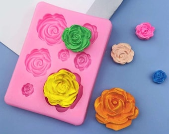 Può includere: Uno stampo in silicone rosa con sei diverse forme di rose. Lo stampo viene utilizzato per creare decorazioni commestibili per torte e cupcake. Ci sono cinque rose finite in diversi colori, tra cui rosa, verde, giallo, arancione e blu.