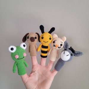 May include: Five finger puppets, including a frog, a dog, a bee, a cat, and a donkey. The puppets are made of crocheted yarn in various colours.