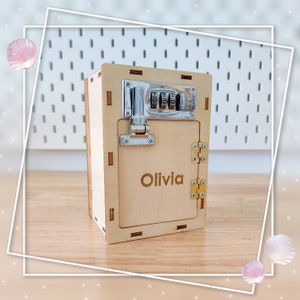 May include: A wooden toy safe with a combination lock and a personalized nameplate that reads "Olivia".