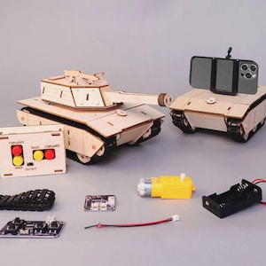 May include: Wooden model tank kit with a remote control, a phone holder, and various electronic components. The kit includes a tank with a long barrel, a remote control with red and yellow buttons, and a black battery holder.
