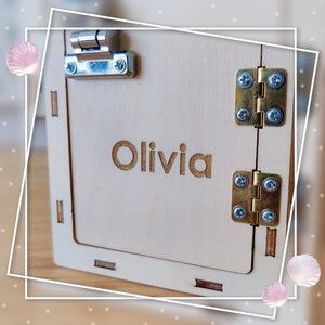 May include: A wooden box with a hinged lid, featuring a brass latch and hinges. The box is personalized with the name "Olivia" engraved on the front.