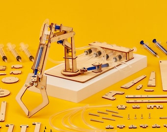 May include: A wooden robotic arm kit with a claw, syringes, and tubing. The kit is assembled on a wooden base and includes various parts for building the arm.
