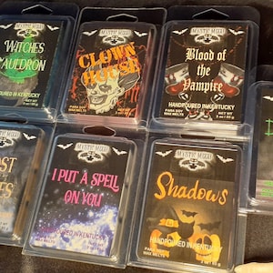 May include: A collection of Halloween-themed wax melts in clear plastic packaging. Each melt features a unique design and spooky name, including "Witches Cauldron," "Clown House," and "Blood of the Vampire." The packaging includes the brand name "Mystic Mood."